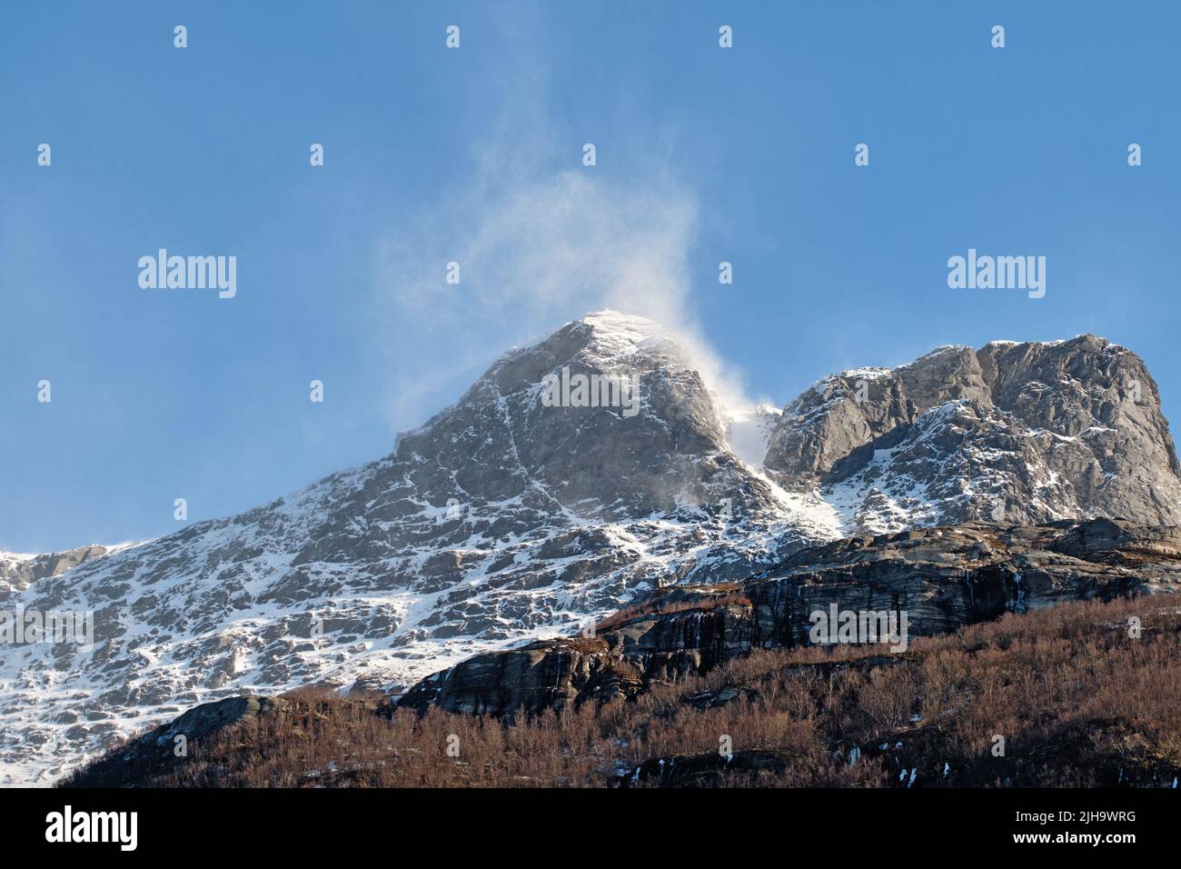 Schöne Landschaft von einem verschneiten Berggipfel mit einem blauen Himmel und Kopierraum. Ein strömender Gipfel mit Frost an einem Winternachmittag. Friedlich und landschaftlich schön Stockfoto