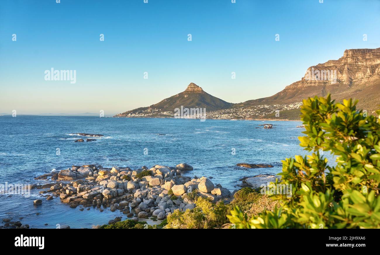 Ein Küstenstrand entlang des Lions Head und des Tafelbergs in Kapstadt, Südafrika, vor blauem Himmel über der Halbinsel. Ruhig und landschaftlich schön Stockfoto