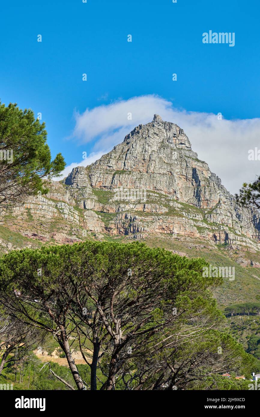 Eine Landschaft eines Berges mit einem wolkigen blauen Himmel Hintergrund und Kopierraum. Friedliche und malerische Aussicht auf einen Gipfel in der Nähe von üppigen grünen Pflanzen und Bäumen Stockfoto