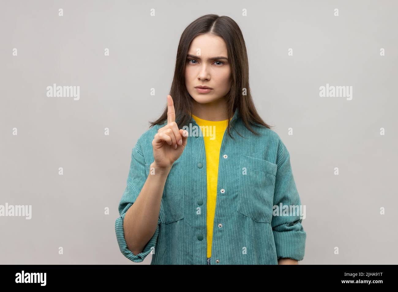 Seien Sie vorsichtig, Porträt von strengen herrischen jungen Frau mit braunen Haaren ernsthaft zeigen Finger nach oben und Warnung, tragen lässige Stil Jacke. Innenaufnahme des Studios isoliert auf grauem Hintergrund. Stockfoto