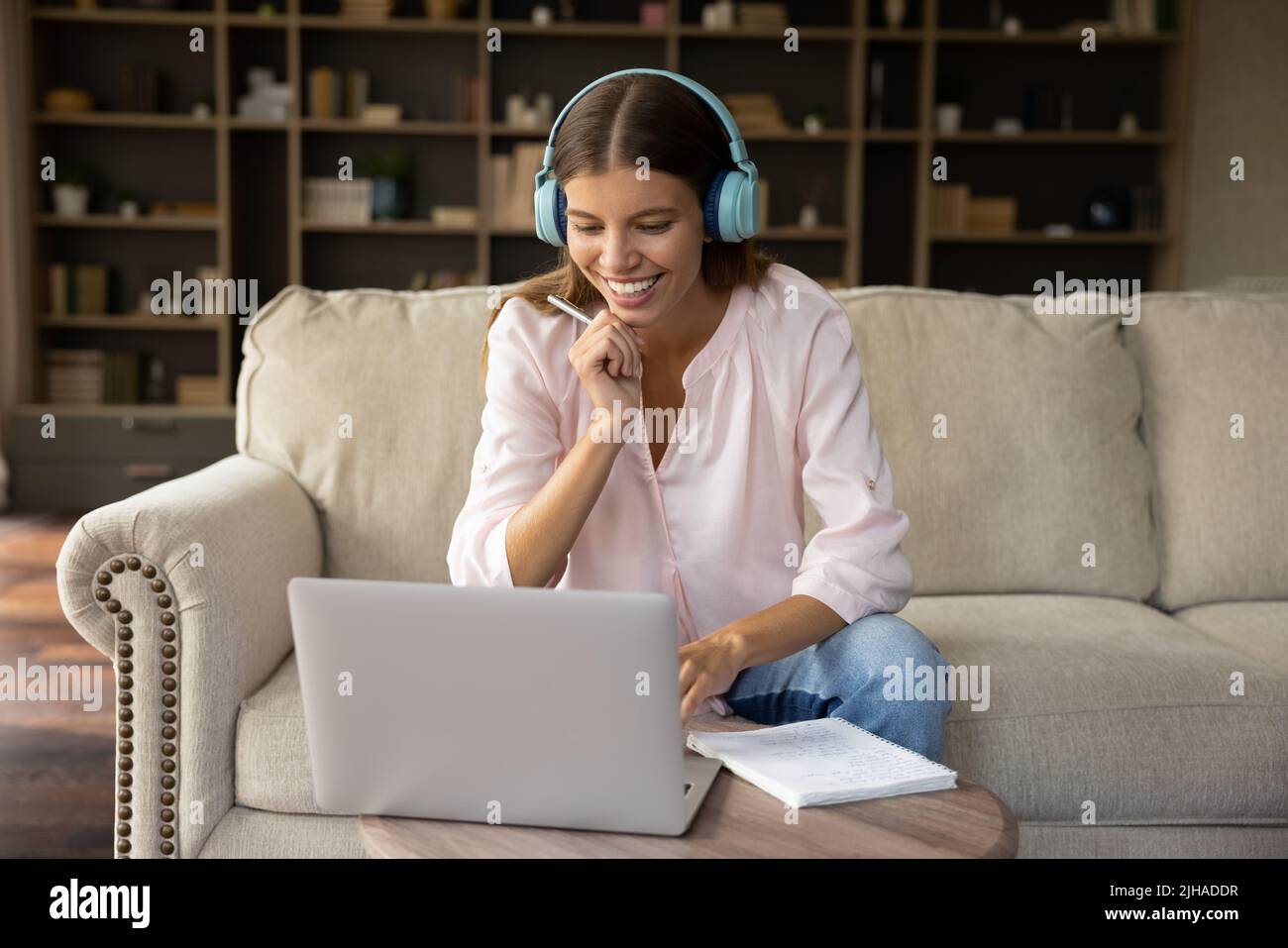 Junge Frau trägt Kopfhörer mit einem Laptop und lernt online zu Hause Stockfoto