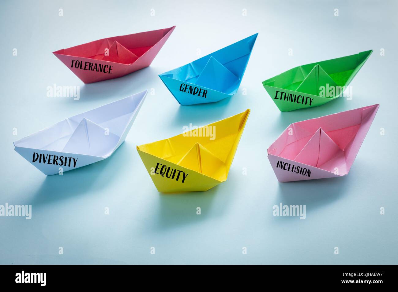 Gleichheit, Identität, Kennzeichnung, Zeichen der Zugehörigkeit. Farbige Papierschiffe der Vielfalt, Gleichheit der Identität, Inklusion mit Worten, Integration, mit einem Blau Stockfoto