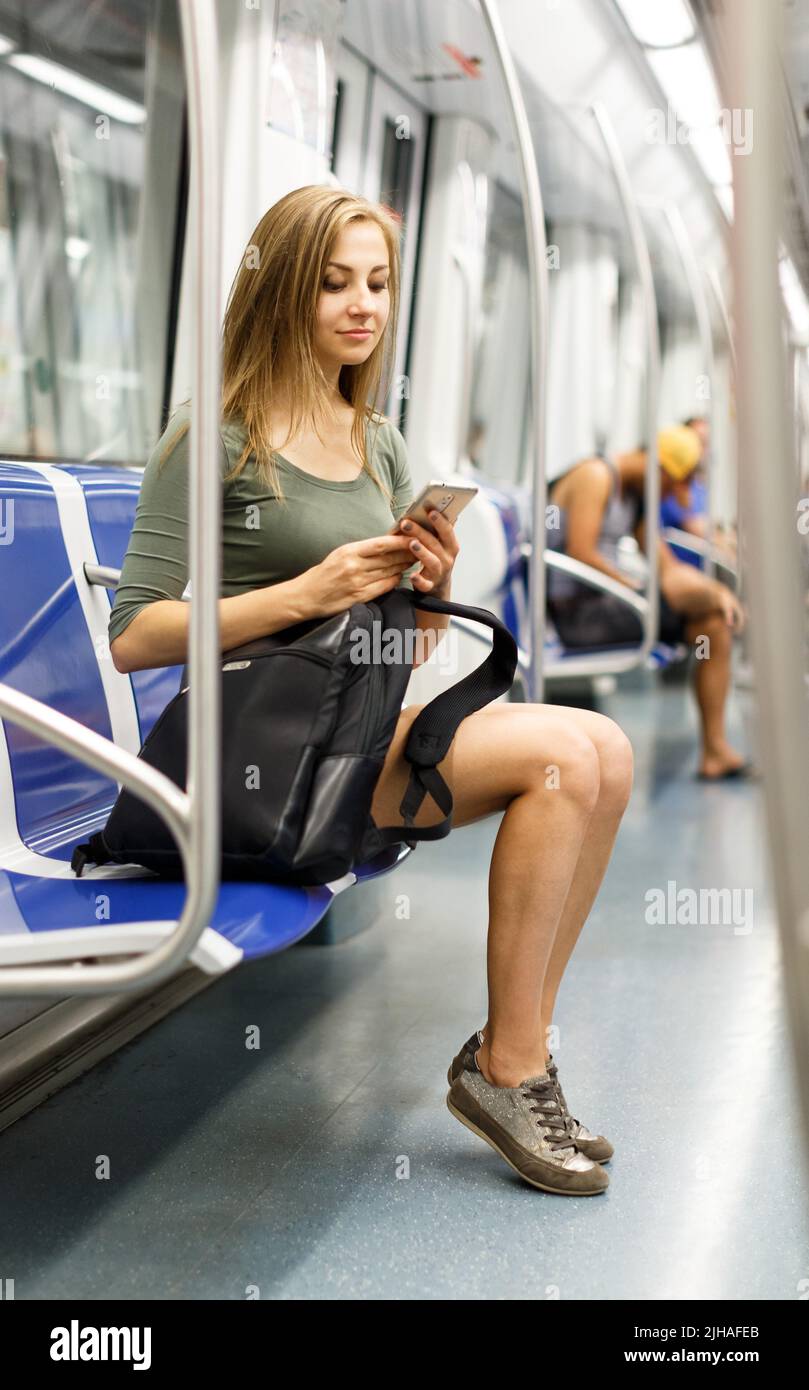 Frau sitzt im Zug und schaut ins Telefon Stockfoto