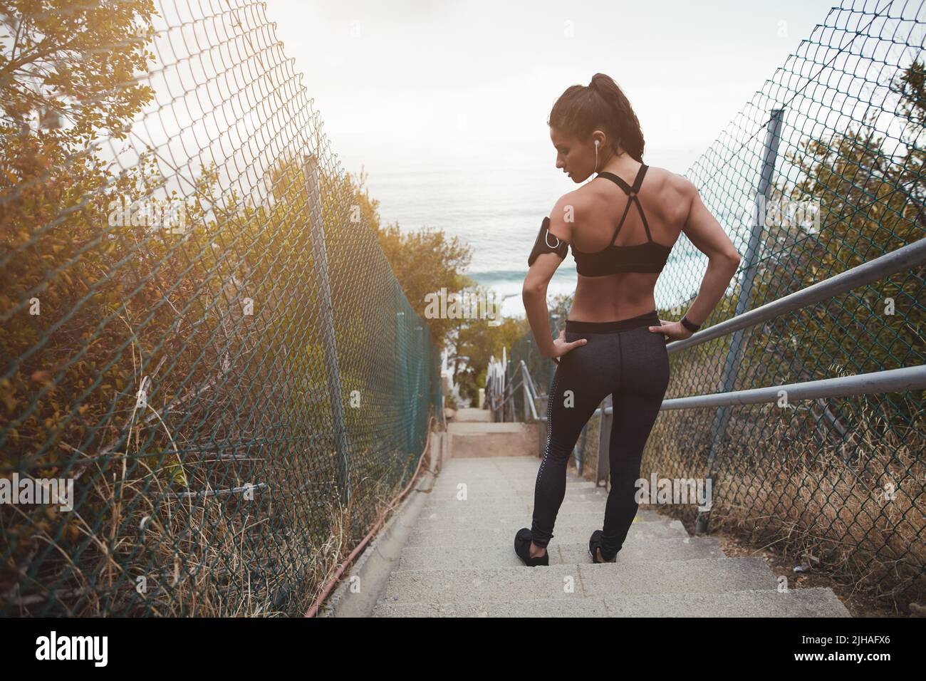 Rückansicht einer muskulösen jungen Frau, die auf einer Treppe im Freien steht. Fit junge Frau, die ein körperliches Training am Morgen. Stockfoto
