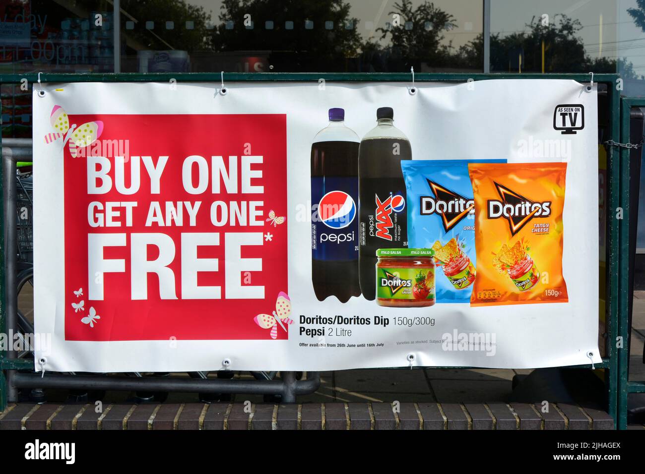 Banner auf Geländern vor dem örtlichen Supermarkt, der für „Buy One Get One“ wirbt, Sonderangebote für Speisen und Getränke (Datumspreise entfernt) England Großbritannien Stockfoto