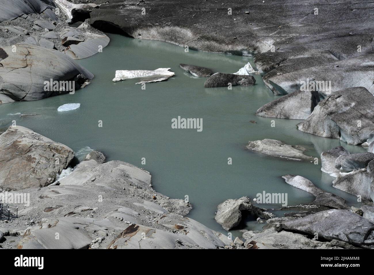 Schmelzwasserpunkt des Rhone-Gletschers, Kanton Wallis, Schweiz. Auf der rechten Seite befinden sich Eisstücke, die vom Gletscher abbrechen. Wissenschaftler geben dem durch die globale Erwärmung verursachten Klimawandel die Schuld daran, dass der sich zurückziehende Gletscher, die Quelle des mächtigen Flusses Rhone, jetzt unter dem Furka-Pass in einer Höhe von etwa 2.208 m / 7.244 ft schmilzt. Im Jahr 1850 erstreckte sich eine Eiszunge weit den Berg hinunter, bevor sie schließlich im Talbecken darunter schmelzte. Stockfoto