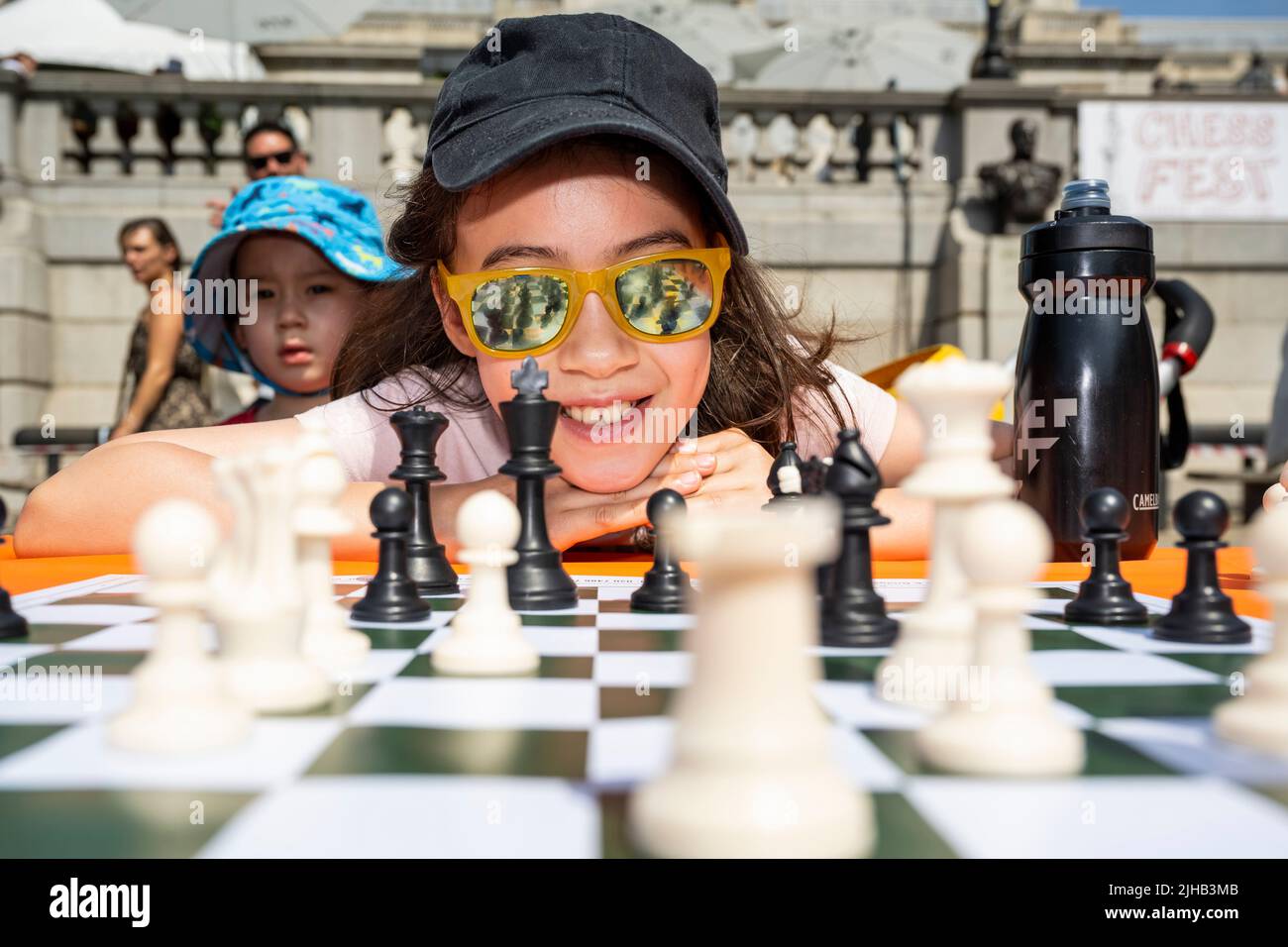 London, Großbritannien. 17. Juli 2022. Ein Mädchen spielt beim Chess Fest auf dem Trafalgar Square Schach. Die Veranstaltung feiert das Schachspiel, bei dem Besucher das Spiel lernen, Schach spielen oder einen Großmeister herausfordern können. In diesem Jahr wird der 50.. Jahrestag des Schachweltmeisterschaftsspiel 1972 zwischen dem Amerikaner, Bobby Fischer und dem Sowjet, Boris Spassky, gefeiert. Ein lebendes Schachset mit 32 professionellen Schauspielern, die die Rolle der Schachfiguren übernehmen, erweckt ikonische Spiele von Garry Kasparov gegen Deep Blue und Bobby Fischer gegen Boris Spassky zum Leben. Kredit: Stephen Chung / Alamy Live Nachrichten Stockfoto