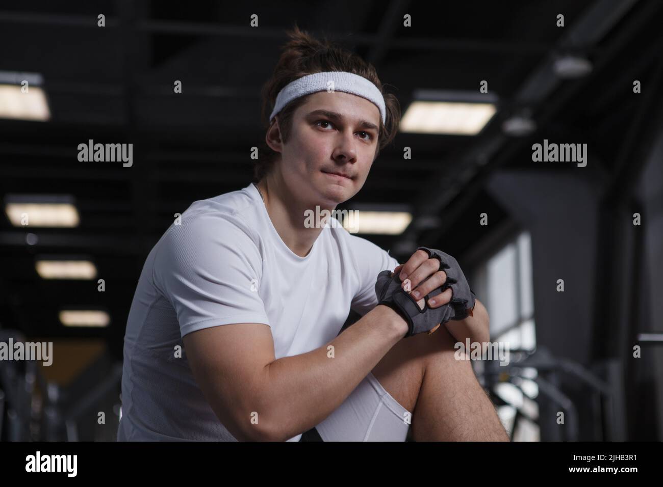 Ein hübscher junger Sportler, der konzentriert aussieht und sich für sein Workout im Fitnessstudio aufwärmt Stockfoto