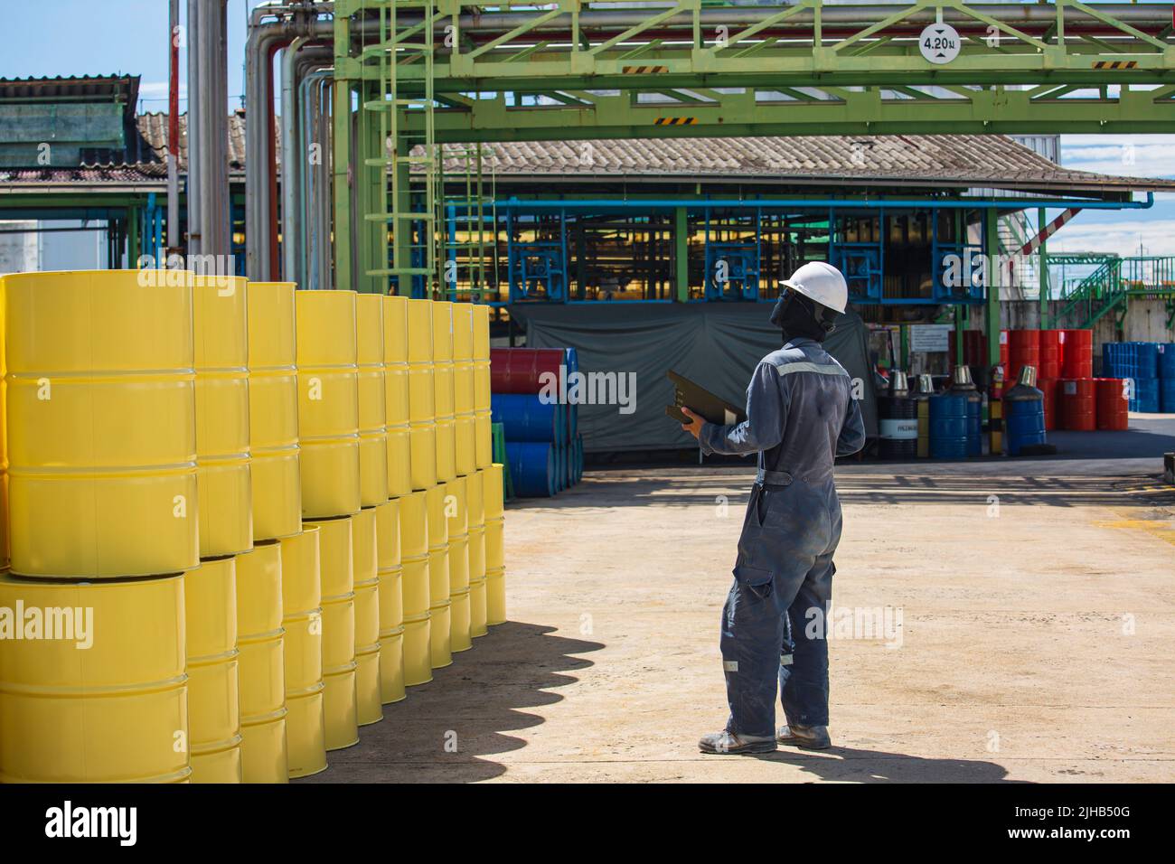 Männliche Arbeiter Inspektion Rekord Fass Öl Lager Fässer gelb vertikal oder Chemikalien für in der Industrie. Stockfoto