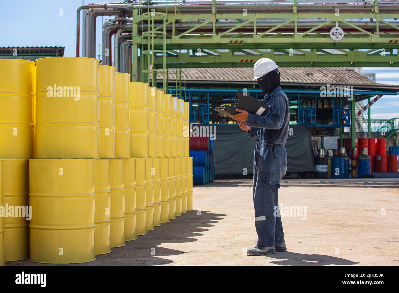 Männliche Arbeiter Inspektion Rekord Fass Öl Lager Fässer gelb vertikal oder Chemikalien für in der Industrie. Stockfoto