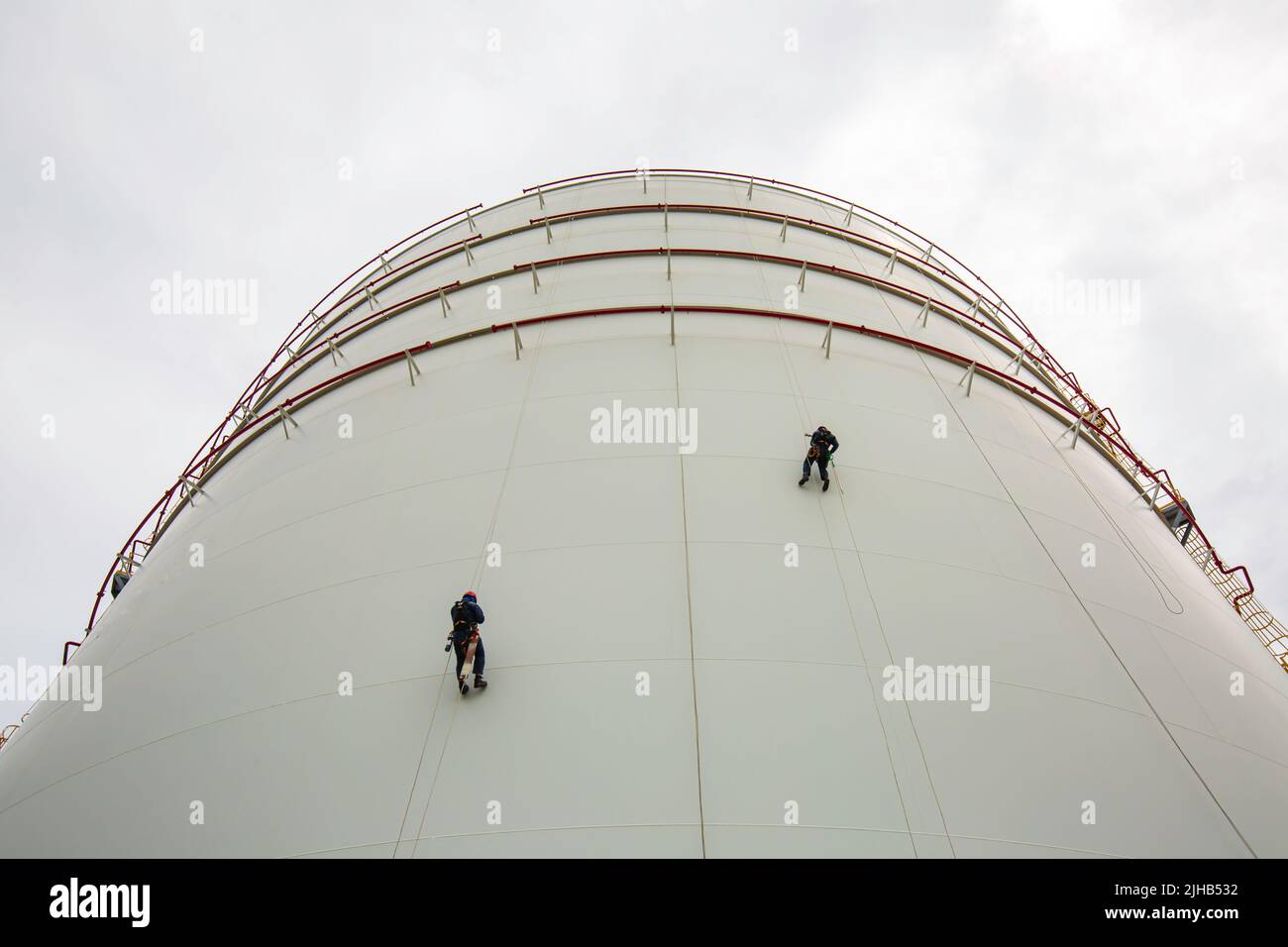 Männliche zwei Arbeiter in der Höhe Tank Shell Platte Seil Leiter Zugang Sicherheitsprüfung der Dicke Speicher Gas Propan. Stockfoto