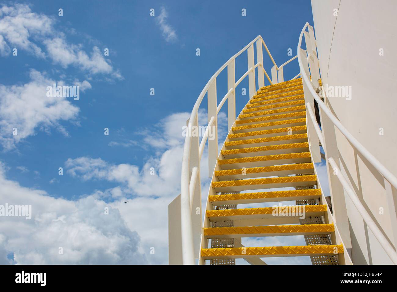 Große Industrietanks für Öl mit einem Gehweg auf und ab der Metalltreppe des Öltanks am blauen Himmel. Stockfoto