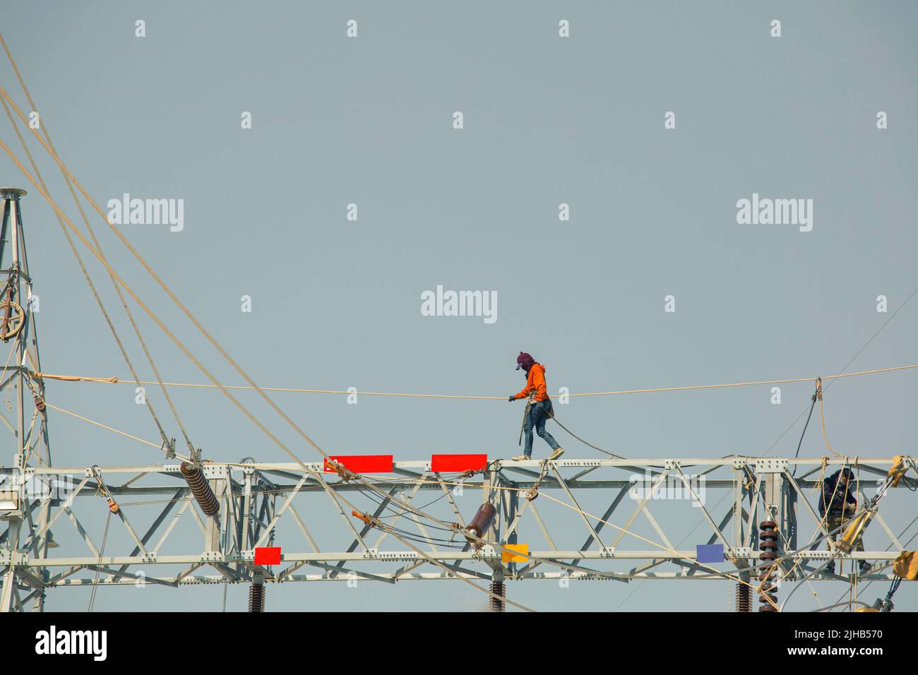 Mann, der auf dem Stahlträger läuft Installation von Hochspannungsübertragungsmasten bei Arbeiten in der Höhe sollte die Sicherheit voll bo getragen werden Stockfoto