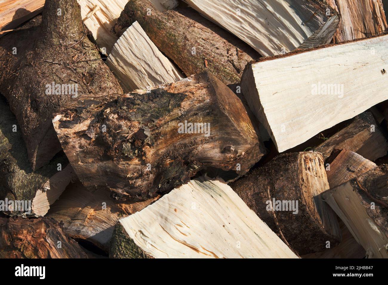 Nahaufnahme eines Stapels geschnittener Holzstämme, die mit einer Axt für Brennholz gespalten und zur Saison überlassen wurden Stockfoto