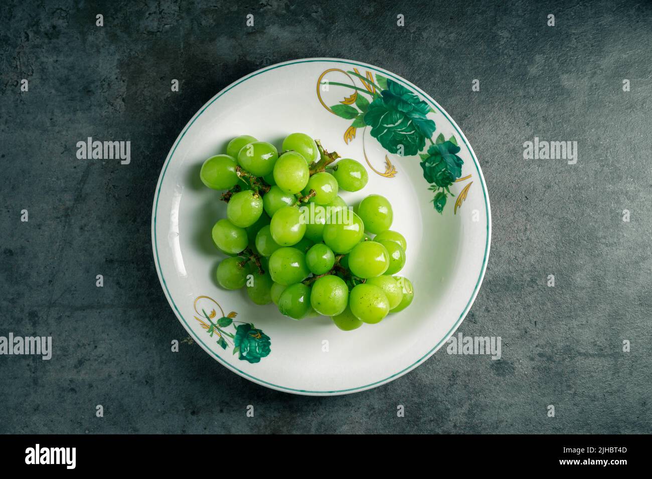Schale aus grünen Trauben isoliert auf grauem Hintergrund. Draufsicht. Aufnahmen im Dunkeln. Ort zum Schreiben. Stockfoto