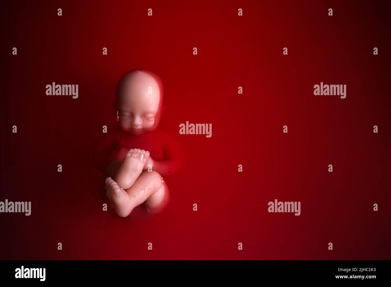 Abtreibungskonzept. Babypuppe im roten Blut sieht aus wie eine Abtreibung. Stockfoto