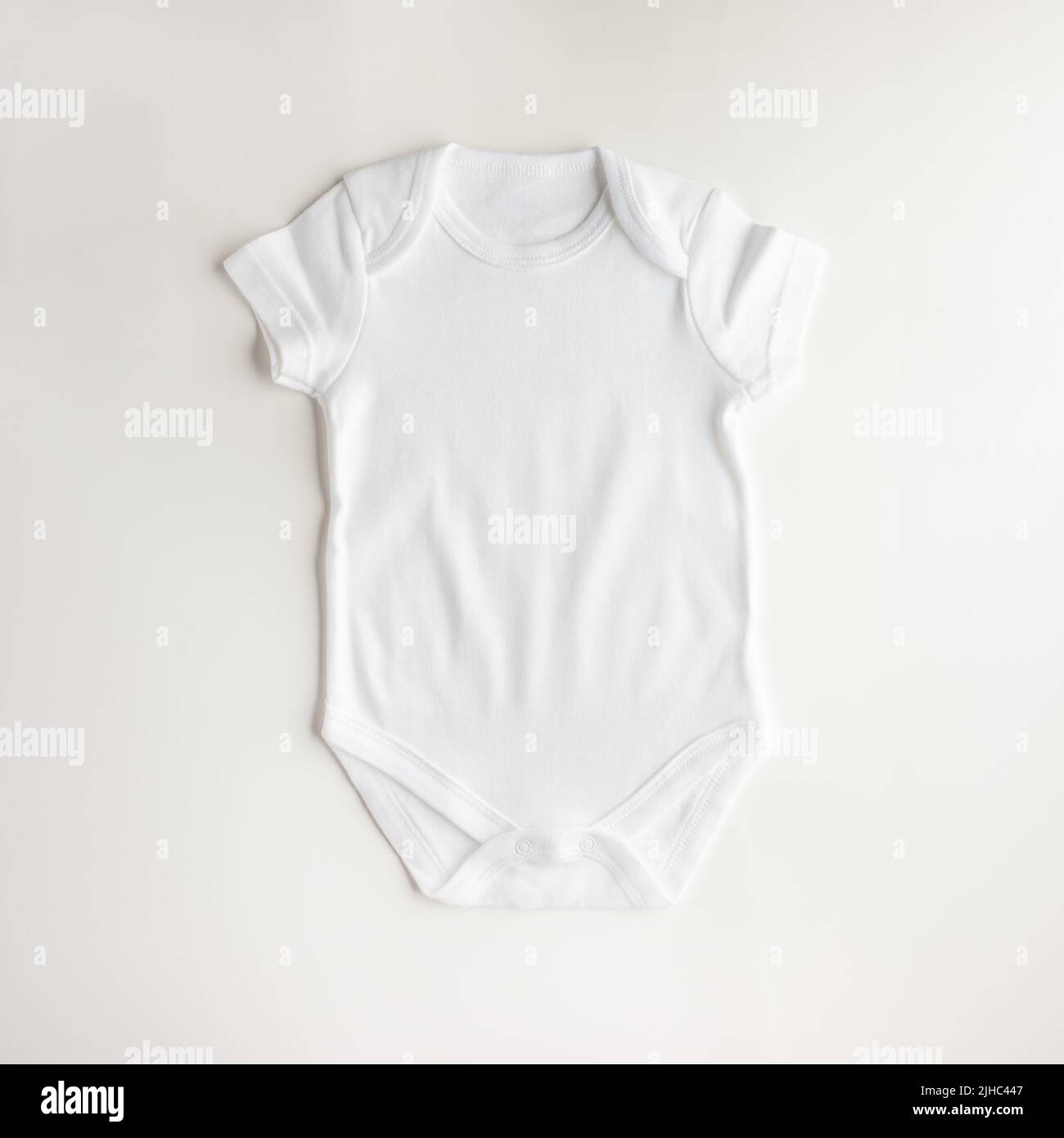 Flacher weißer Body für neugeborene Jungen und Mädchen auf weißem Hintergrund. Einfache, bequeme Babykleidung aus Naturstoff. Layout für pla Stockfoto