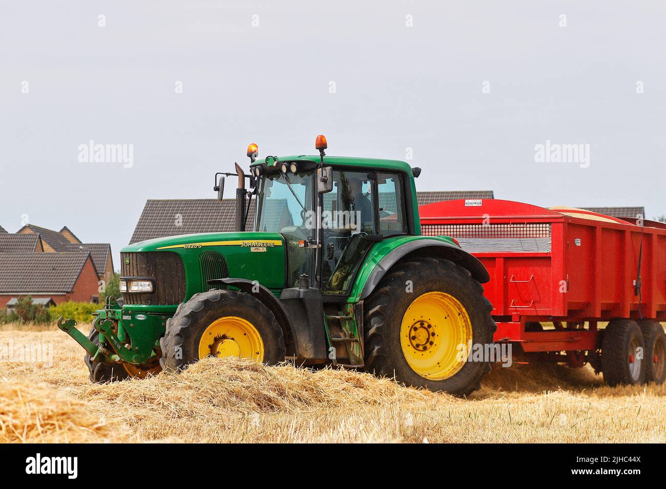 Ein John Deere 6920S Traktor wartet darauf, mit Erntegut von einem Mähdrescher beladen zu werden Stockfoto