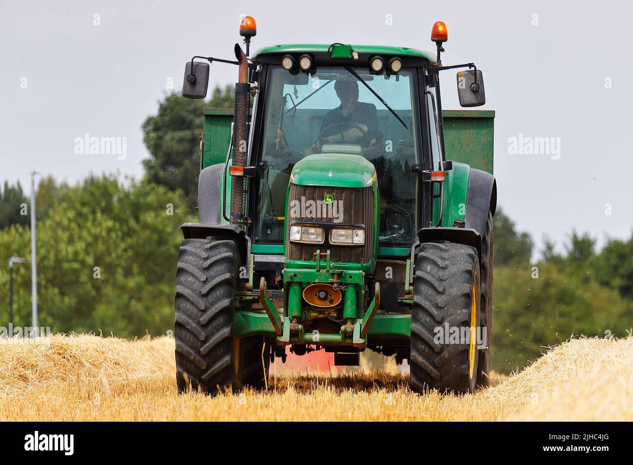 Ein John Deere 6920S Traktor wartet darauf, mit Erntegut von einem Mähdrescher beladen zu werden Stockfoto