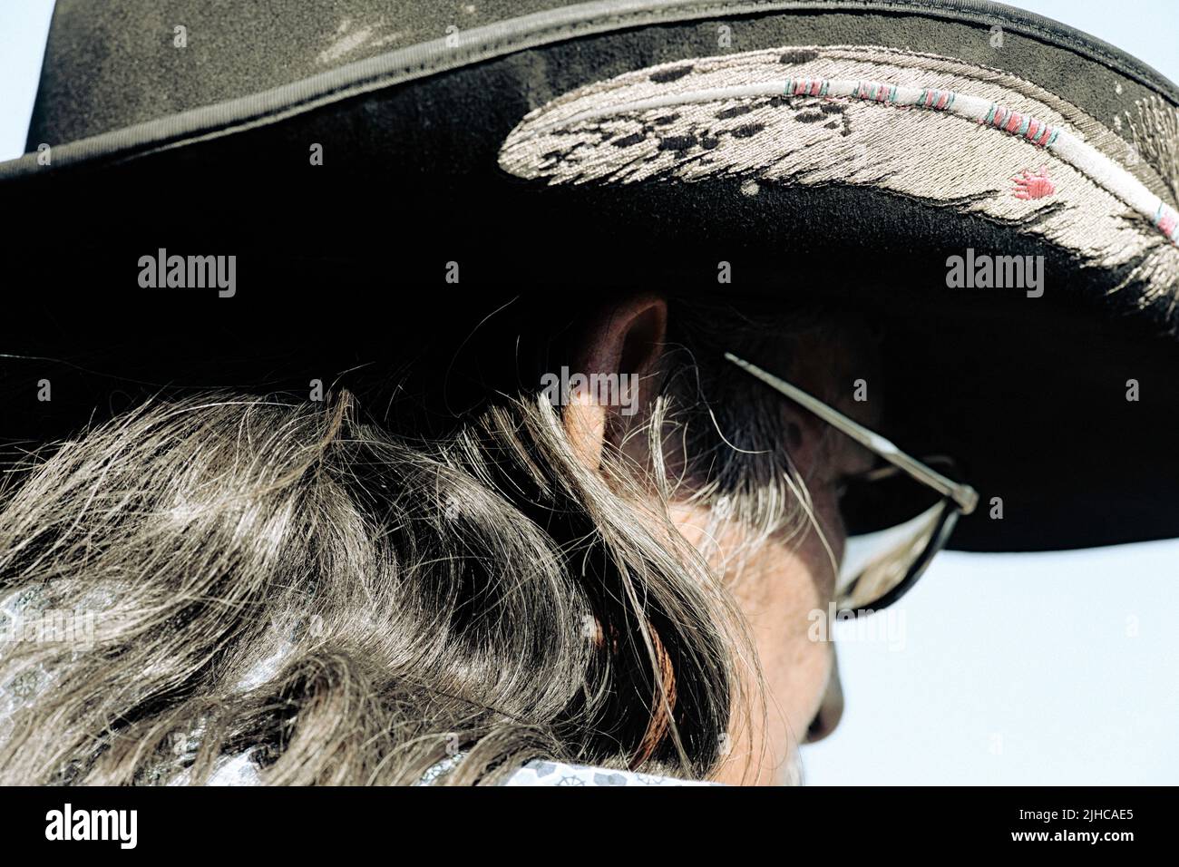 Ein Nahaufnahme-Foto eines Indianers mit indianischer Ureinwohner, der einen Cowboyhut trägt, der mit einer Feder bestickt ist Stockfoto