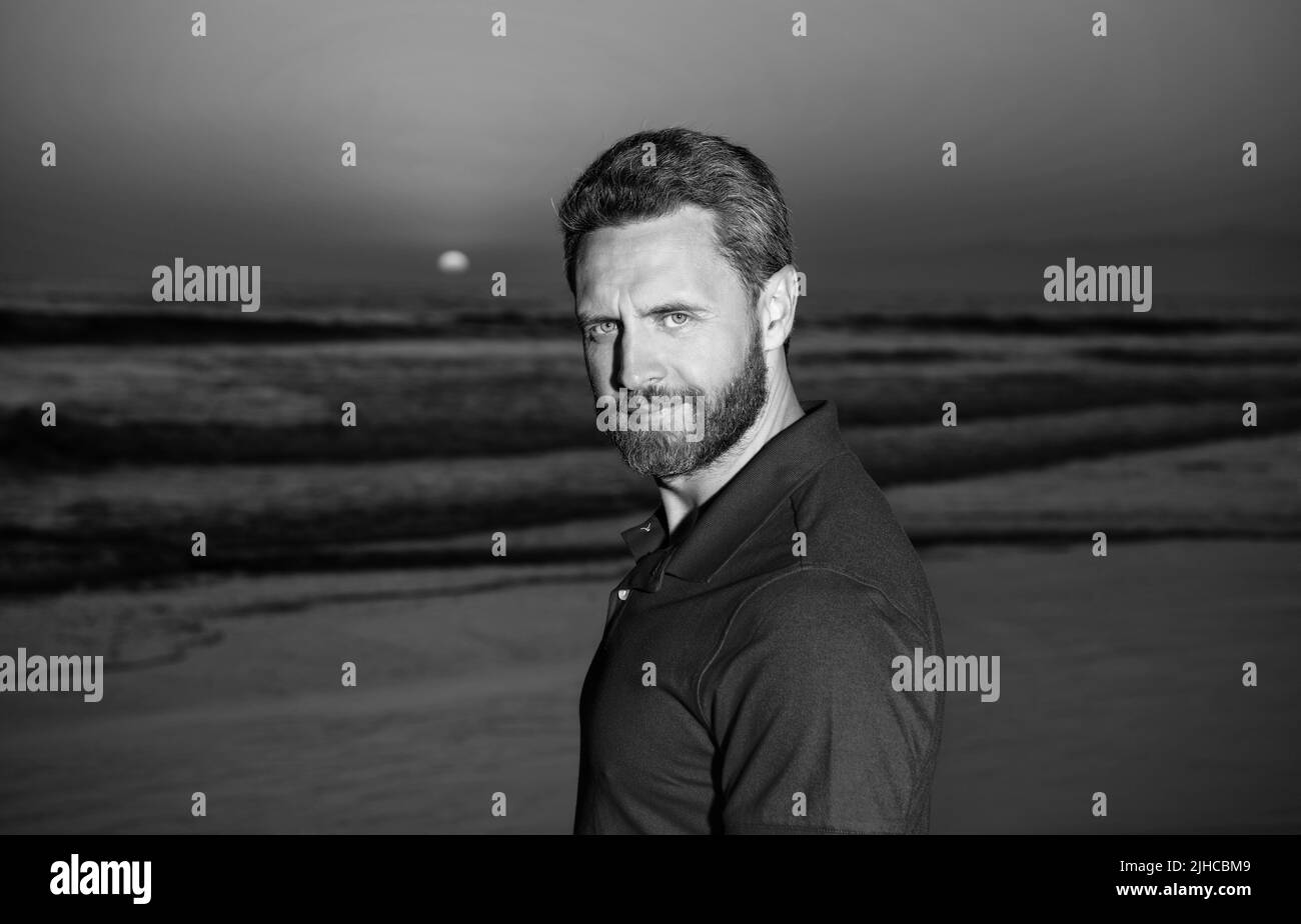 Porträt eines lächelnden Mannes über dem Meer am Sommerstrand bei Sonnenaufgang, Sommerzeit Stockfoto