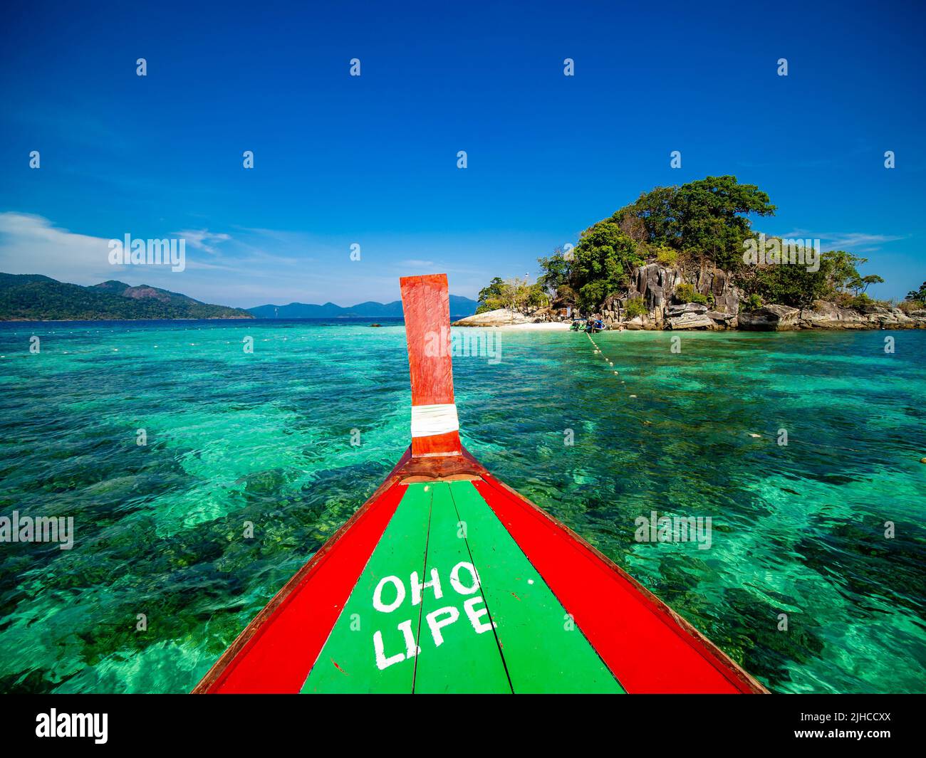 Nahaufnahme eines Bogens eines Holzbootes, das an einem sonnigen Tag auf türkisfarbenem Wasser in roten und grünen Farben gefärbt ist Stockfoto