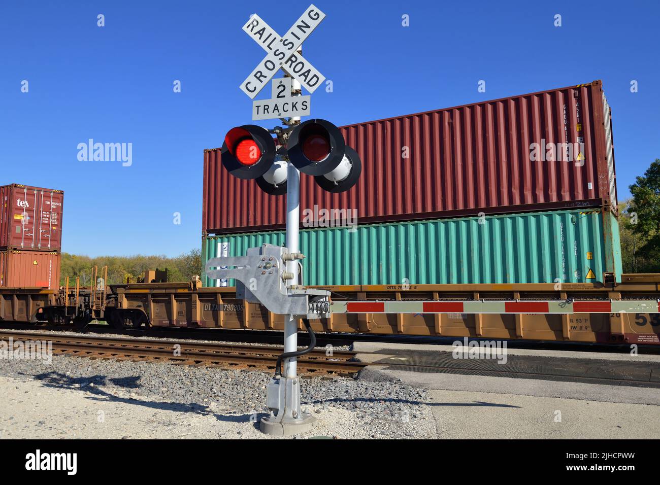Hoffman Estates, Illinois, USA. Blinkende Signale an einem Bahnübergang, der durch das Gerät geschützt ist, wenn ein intermodaler Güterzug vorbeifährt. Stockfoto