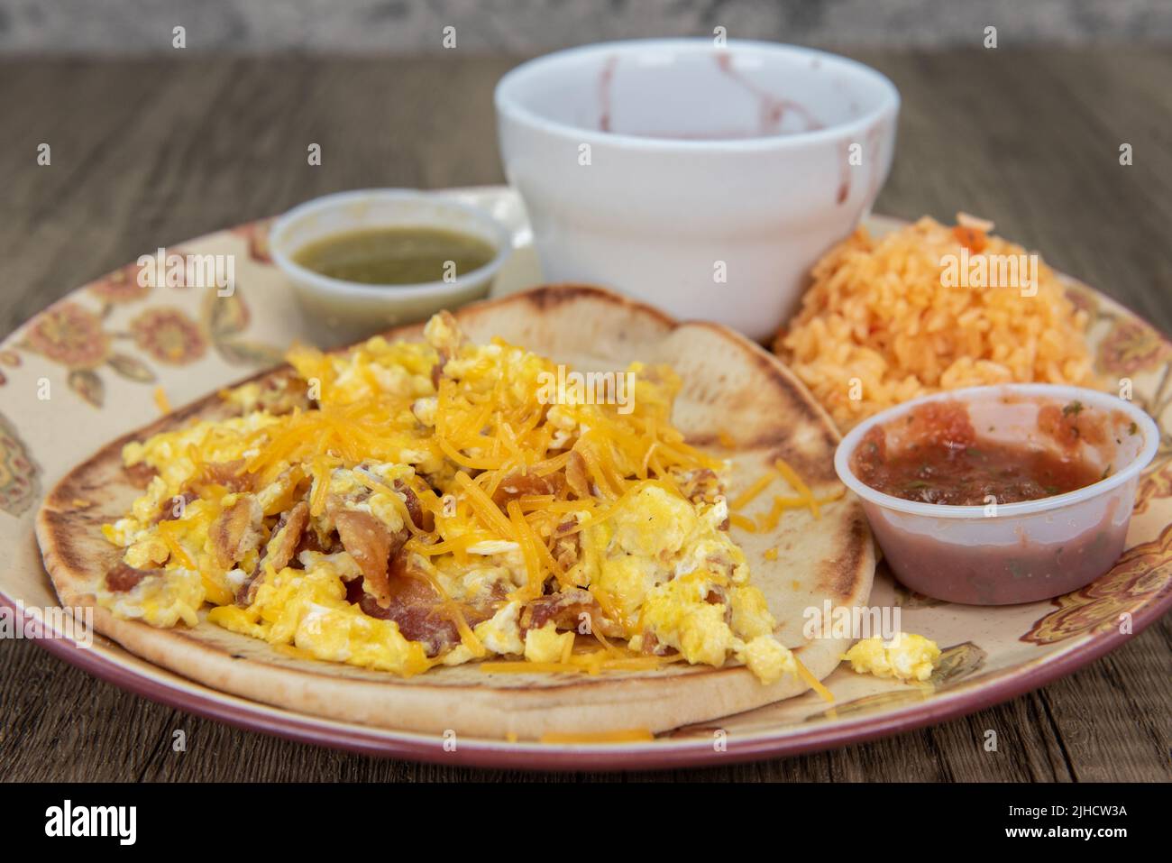 Dicke hausgemachte Tortilla hält ein Frühstück Taco mit geschmolzenem Käse bedeckt, Koriander und Salsa Dipping Sauce für eine vollständige Füllung Mahlzeit. Stockfoto