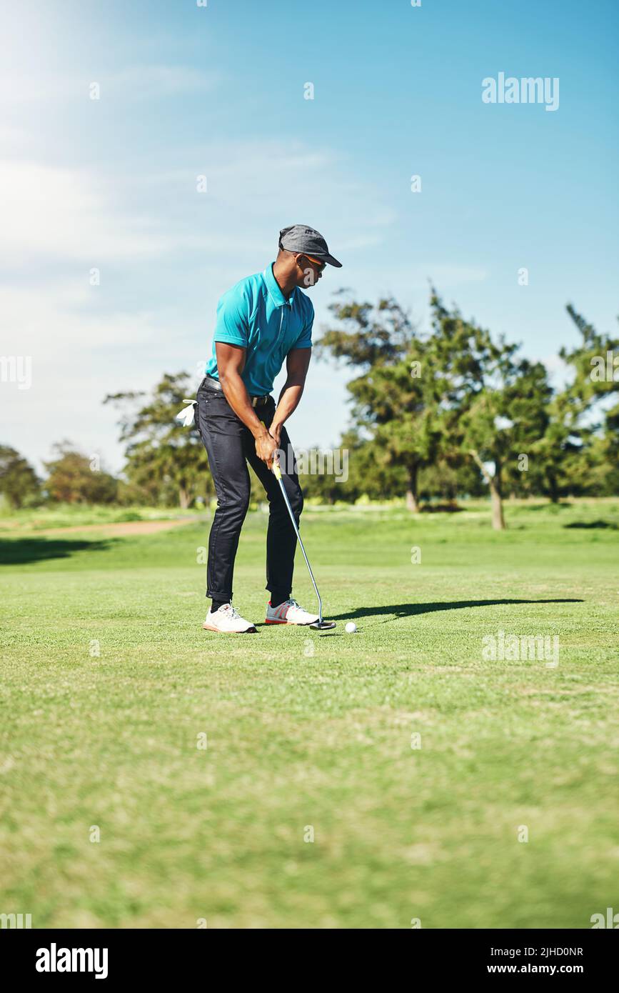 Jetzt sanft. Ein fokussierter junger Golfer, der tagsüber auf einem Golfplatz draußen einen Schuss mit seinem Putter spielen wird. Stockfoto