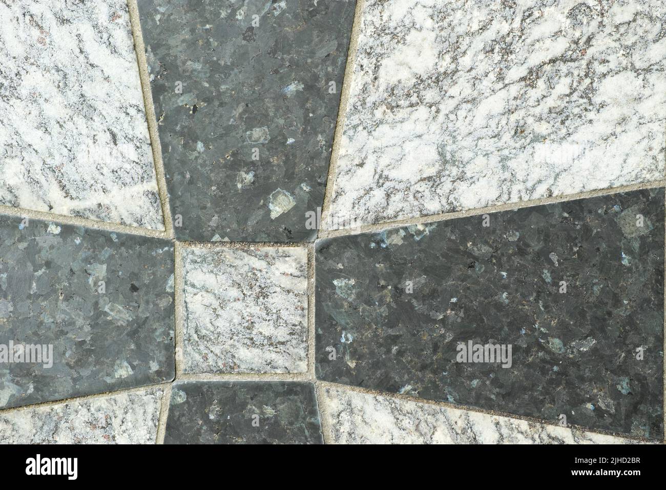 Nahaufnahme von schwarzen und grauen Granitfliesen auf einem Boden. Kreatives Architekturdesign von Granitfliesen, die zu einem Kreuzmuster zementiert sind. Textur Stockfoto