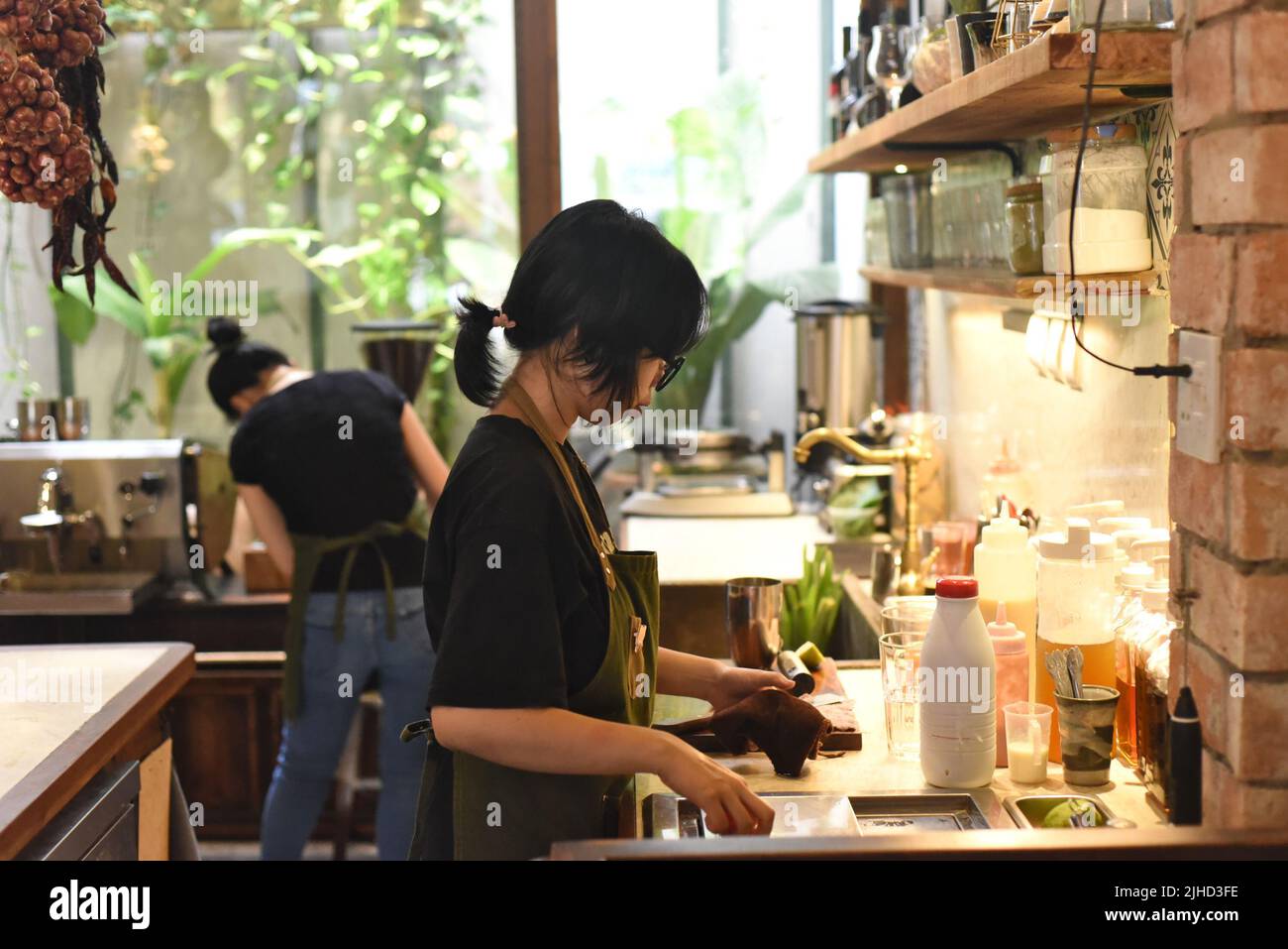 Vietnamesische Kellnerin, die eine Bestellung in einem Café vorbereitet Stockfoto