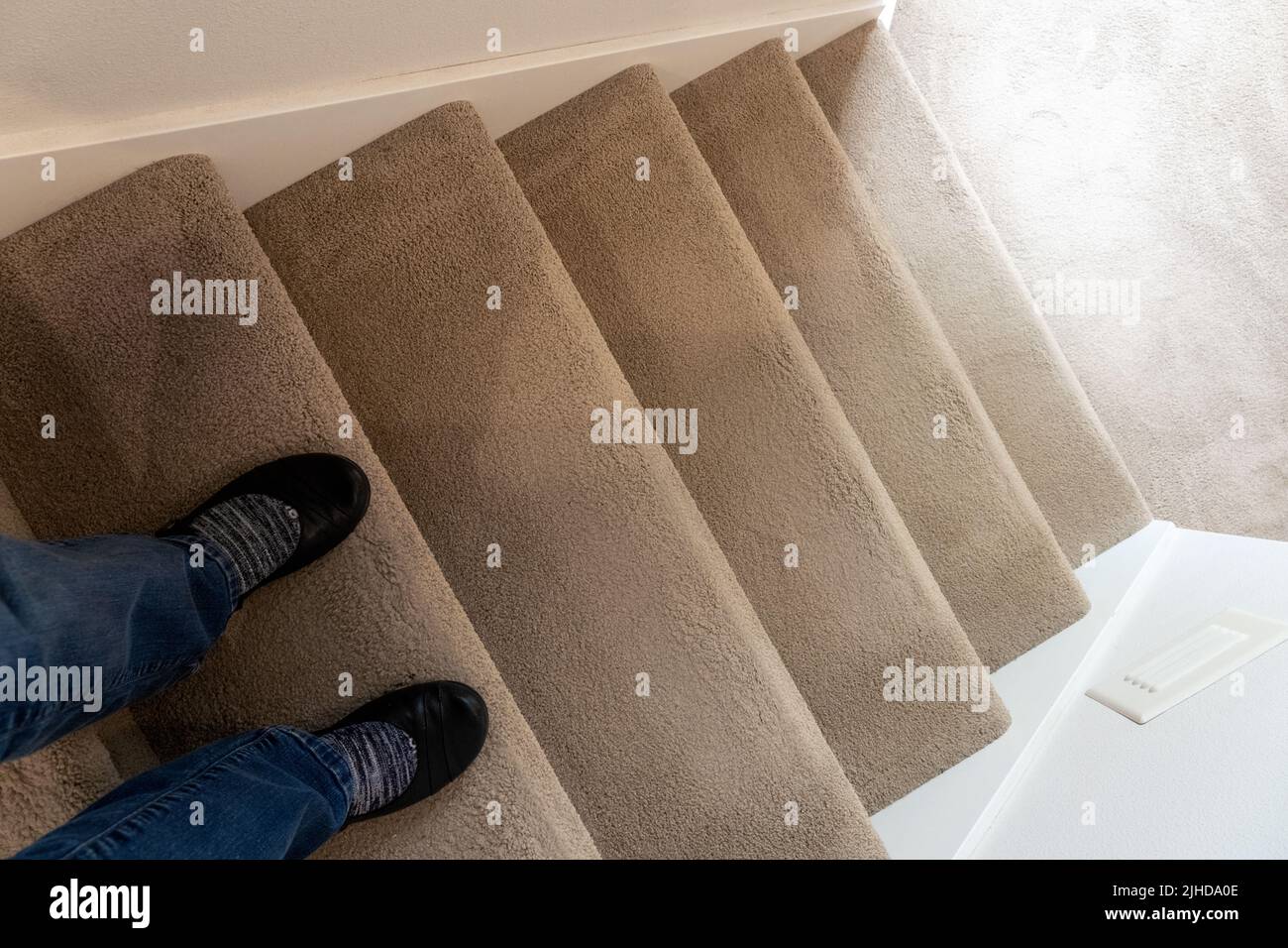 Issaquah, Washington, USA. Beine und Füße einer Frau, die auf einer Treppe mit Teppich steht, in der Hoffnung, dass das Ziel ein hellerer Ort ist Stockfoto