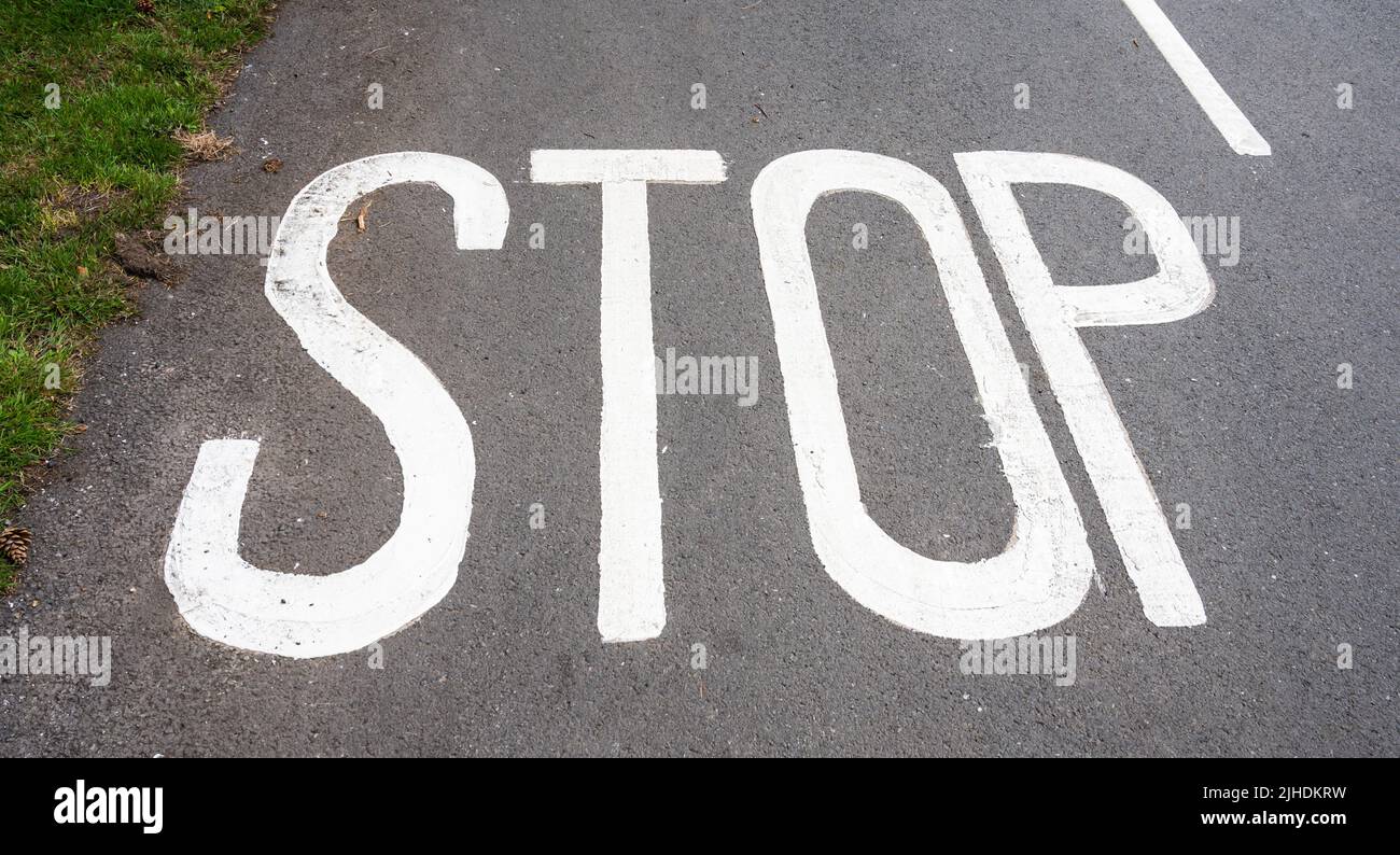 In einer Straße in Großbritannien weiß lackiertes Stoppschild. Stockfoto