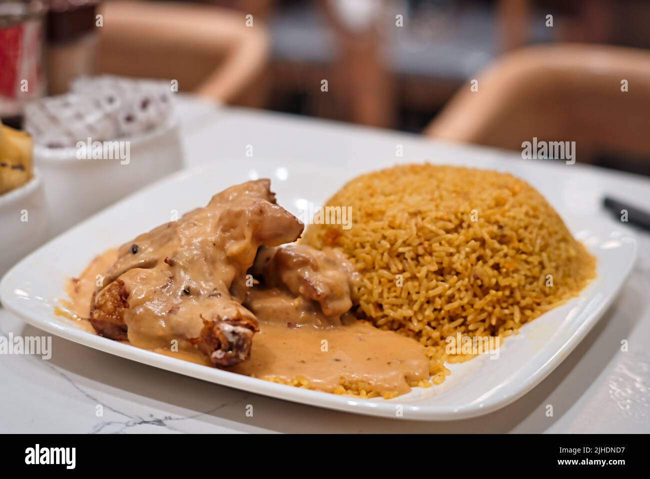 Ein flacher Fokus eines köstlichen Hühnerschenkels mit etwas Reis in einem Restaurant Stockfoto