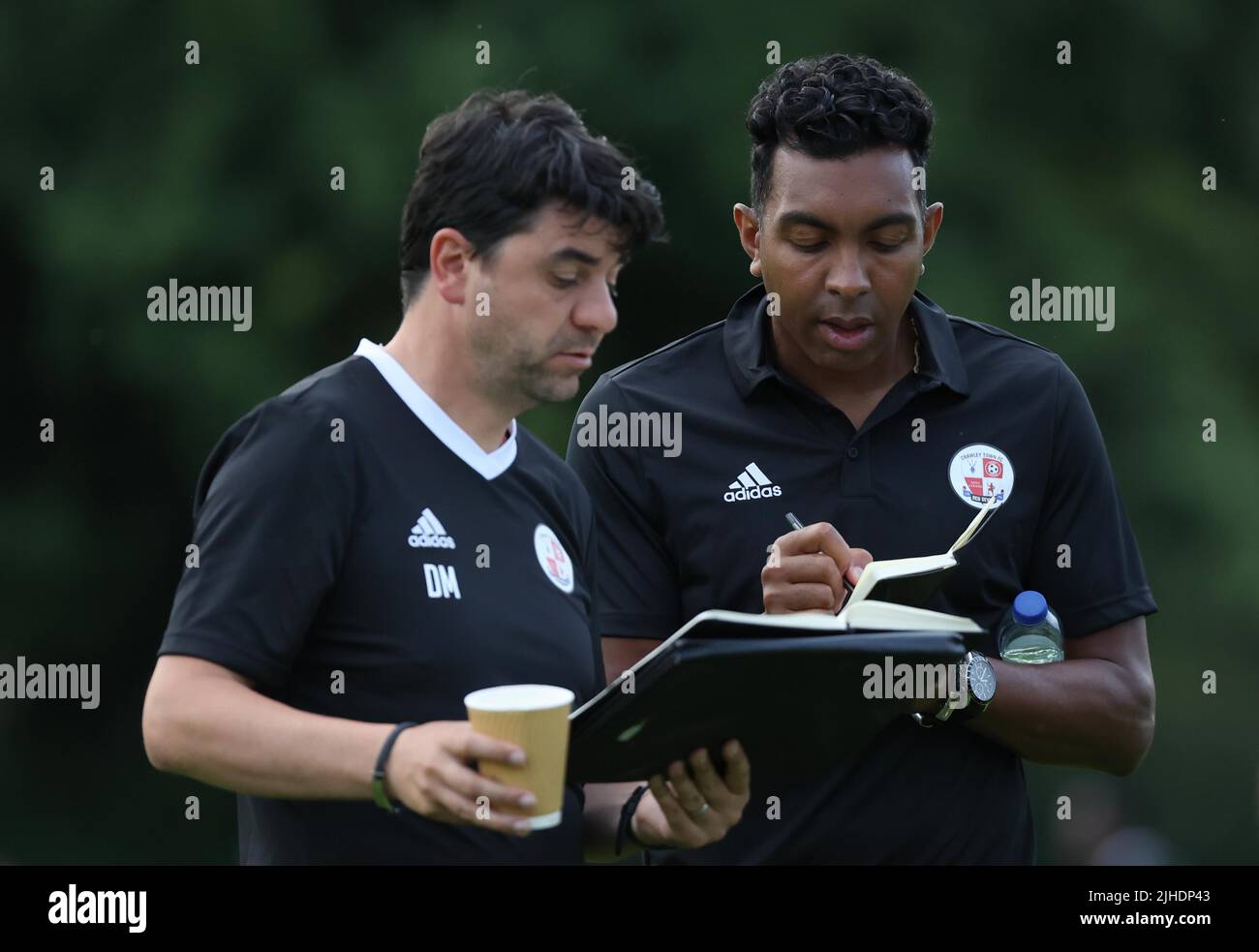 Crawley Town Manager Kevin Betsy (R) spricht mit dem Trainer Dan Micciche, der während der Vorsaison zwischen dem Three Bridges FC und dem Crawley Town FC auf dem Jubilee Field in Three Bridges am 13.. Juli 2022 zu sehen war Stockfoto