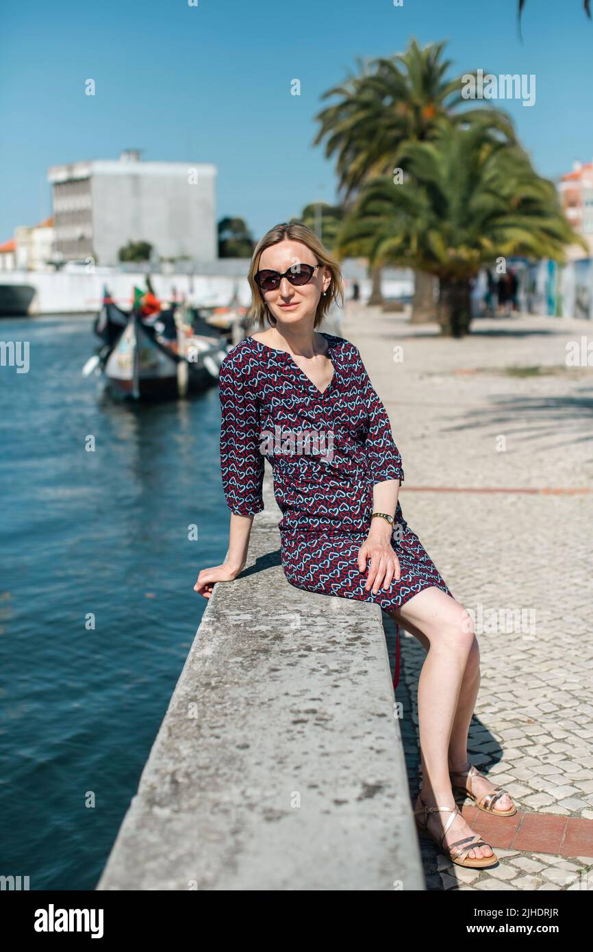 Eine Touristenfrau sitzt an einer Kanalpromenade in Aveiro, Portugal. Stockfoto