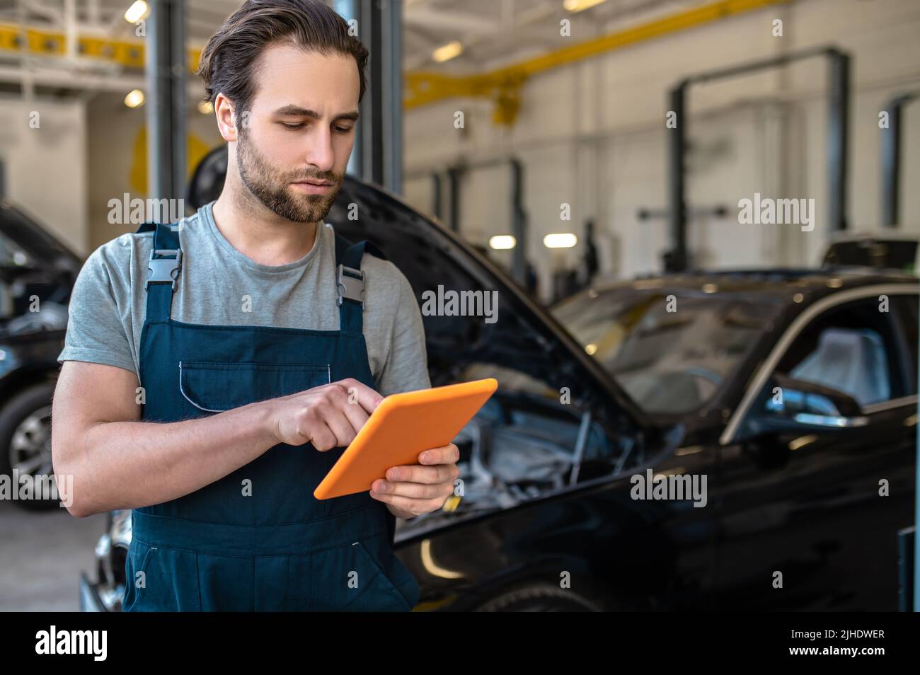 Automechaniker, der das Tablet in der Werkstatt betrachtet Stockfoto