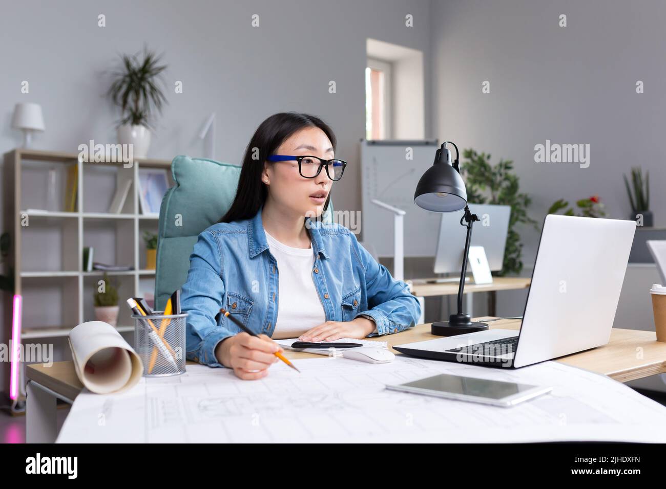 Junge schöne asiatische Frau Architektin Designer trägt Brille am Desktop-Computer arbeiten und Zeichnung mit Bleistift, arbeiten an Projekt. Stockfoto