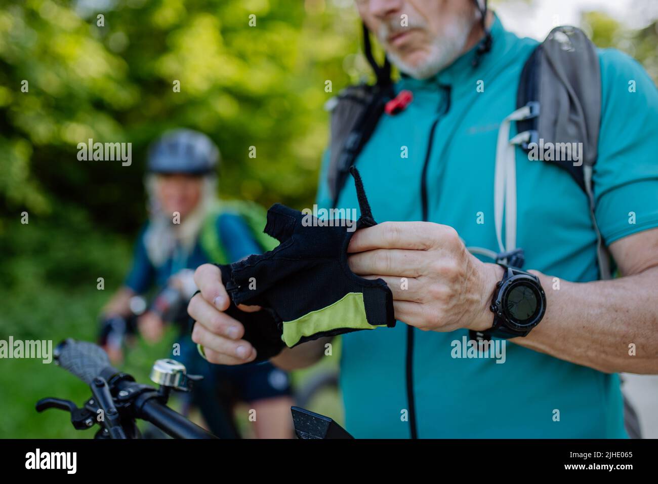 Nahaufnahme eines älteren Motorradfahrers, der in der Natur Fahrradhandschuhe anlegt. Stockfoto