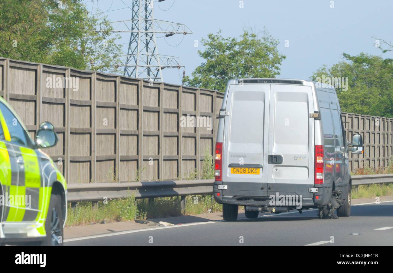 Highways Traffic Officer hilft einem gestrandeten Van auf einer Fahrspur einer intelligenten Autobahn mit einem verschlechterten Reifen. Stockfoto