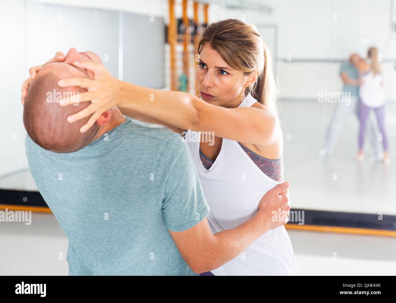 Die sportliche Frau mit Trainer nimmt im Fitnessstudio schmerzhafte Augenaufenthalten auf Stockfoto