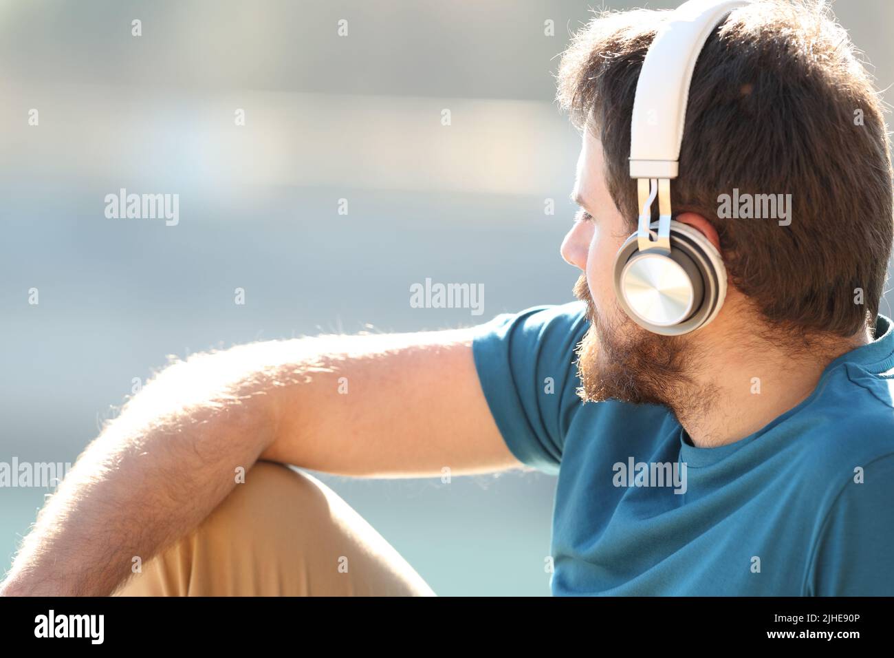 Rwelaxed Mann, der Musik mit Kopfhörern hört und die Ansichten in der Natur betrachtet Stockfoto