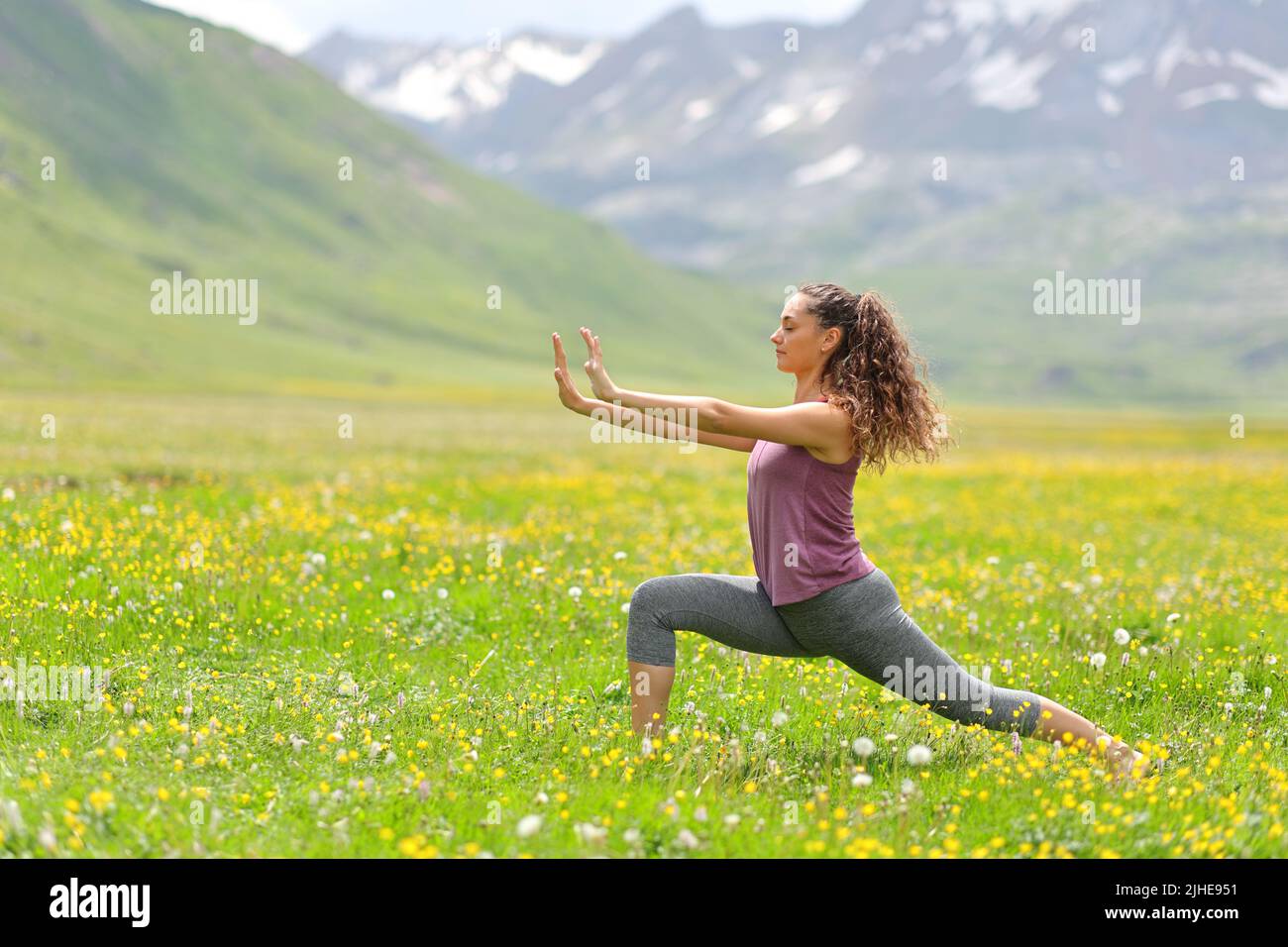 Profil einer Frau, die in einem hohen Bergfeld Tai Chi praktiziert Stockfoto