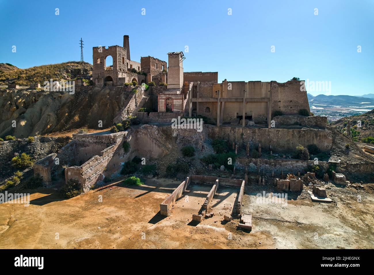 Luftaufnahme, Drohne aus Sicht alte verlassene Gebäude von Minen von Mazarron in Murcia auf blauem Himmel Hintergrund während sonnigen Sommertages. Absaug von Mineralien Stockfoto