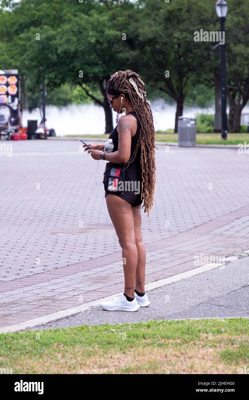 Eine Frau in sportlicher Kleidung und mit sehr langen Haarverlängerung. Im Flushing Meadows Corona Park in Queens, New York. Stockfoto