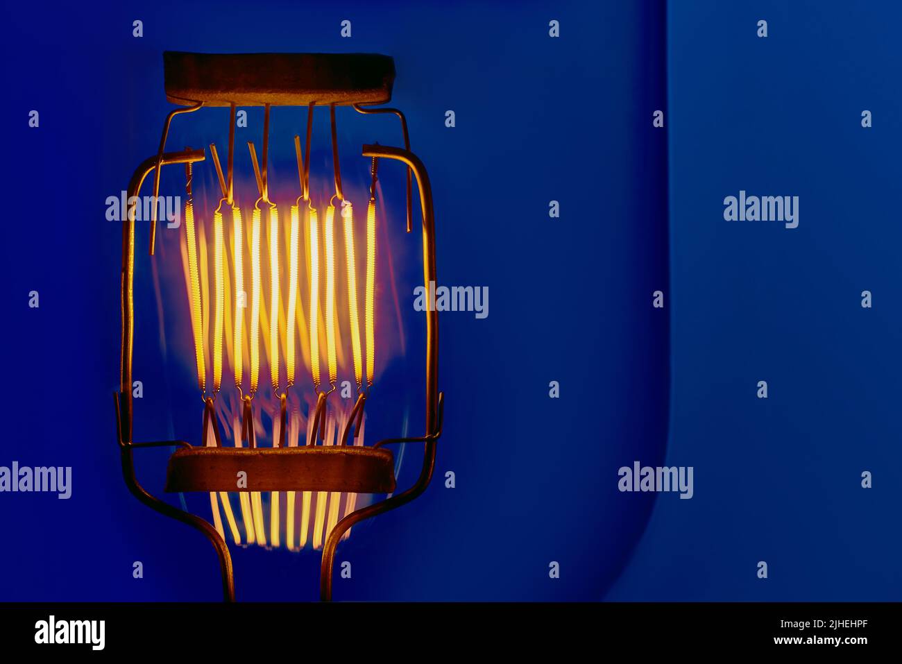Wolfram-Filament von Hochleistungs-Glühlampe auf blauem Hintergrund Nahaufnahme mit Copyspace Stockfoto