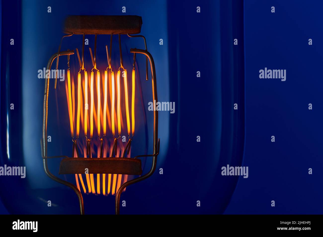 Wolfram-Filament von Hochleistungs-Glühlampe auf blauem Hintergrund Nahaufnahme mit Copyspace Stockfoto