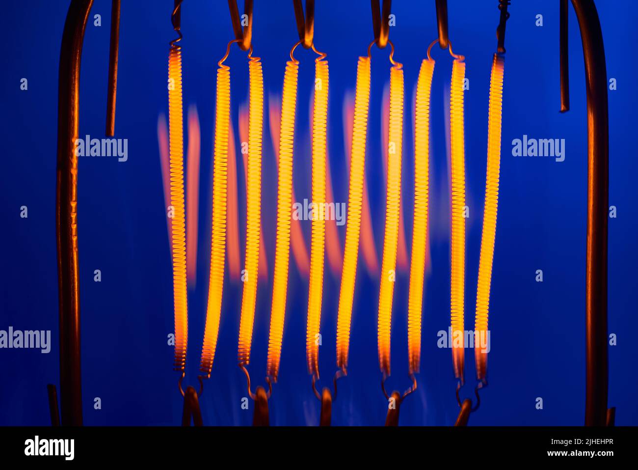 Wolfram-Filament von Hochleistungs-Glühlampe auf blauem Hintergrund Nahaufnahme Stockfoto