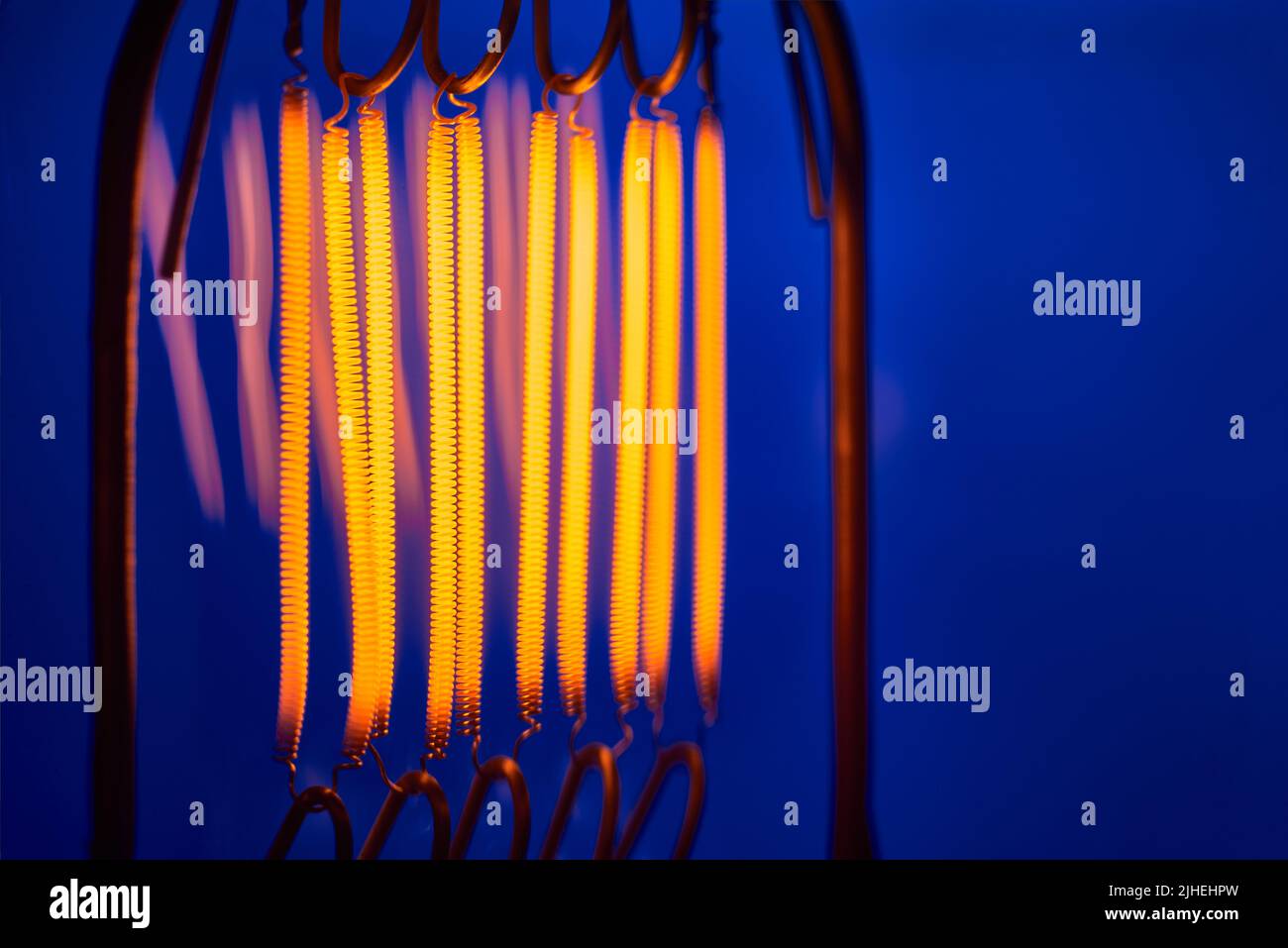 Wolfram-Filament von Hochleistungs-Glühlampe auf blauem Hintergrund Nahaufnahme Stockfoto