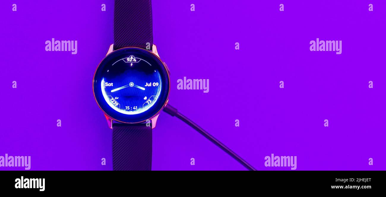 Smart Uhr auf drahtlose Aufladung mit On-Screen.Purple, veri peri Neon, glühende trendige Farbe background.Top view.Copy space.Banner, Werbung.Indoors Stockfoto